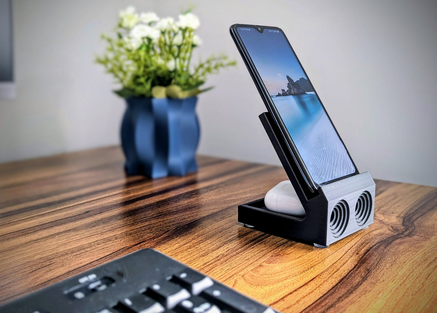 Phone stand with acoustic booster. Back tray ideal for storing air pods or earbuds. Comes in a variety of colors and may be customized for the dimensions of any device.