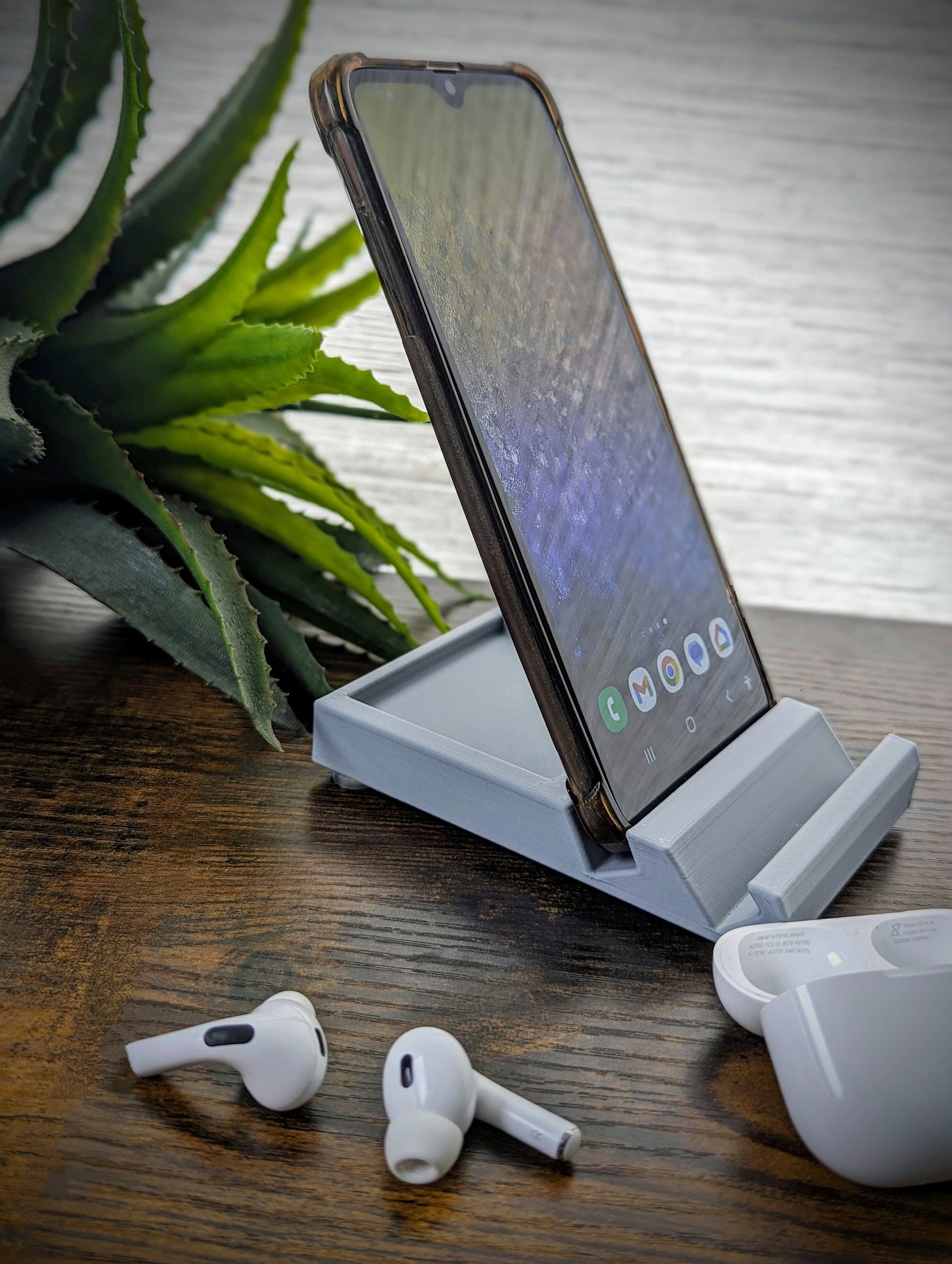 Minimalist phone holder with two display vantage angles. Back tray ideal for storing air pods or earbuds. Comes in a variety of colors and may be customized for the dimensions of any device.