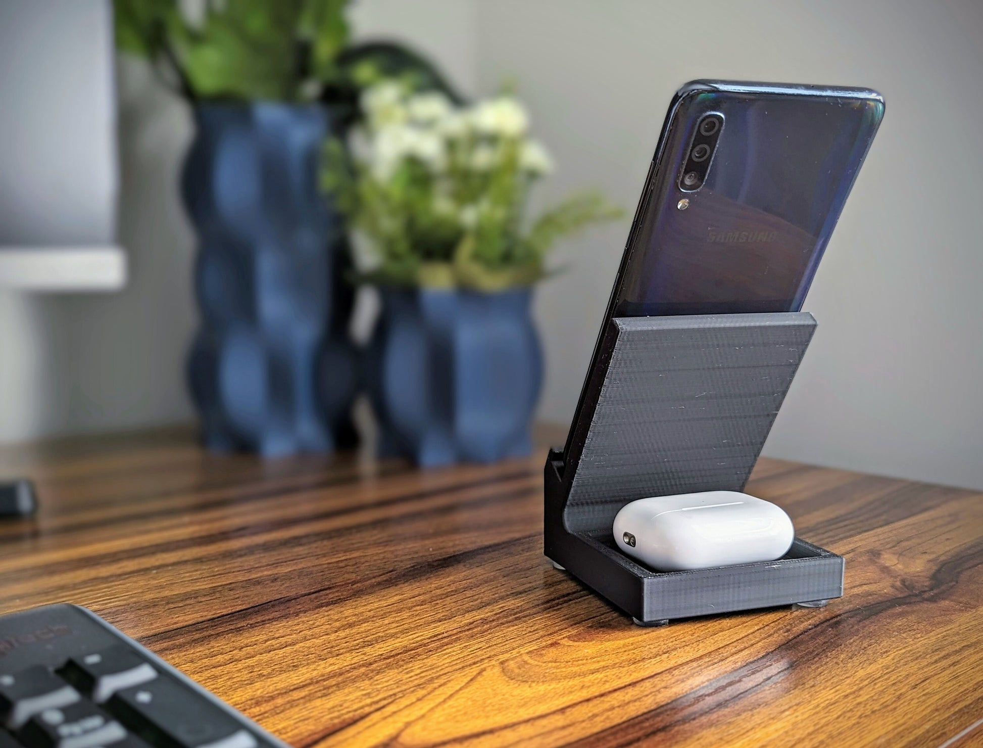 Phone stand with acoustic booster. Back tray ideal for storing air pods or earbuds. Comes in a variety of colors and may be customized for the dimensions of any device.