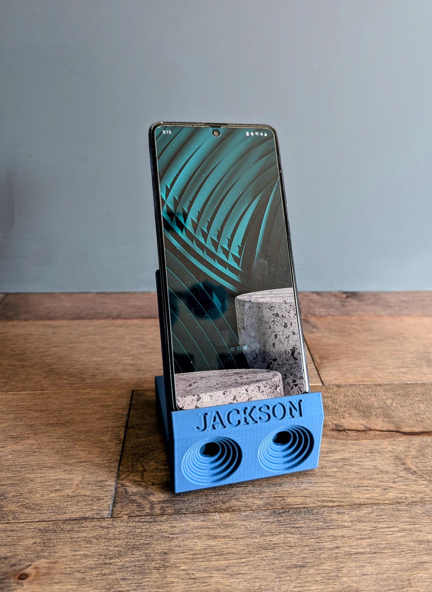 Phone stand with acoustic booster. Back tray ideal for storing air pods or earbuds. Comes in a variety of colors and may be customized for the dimensions of any device. Personalized with name.