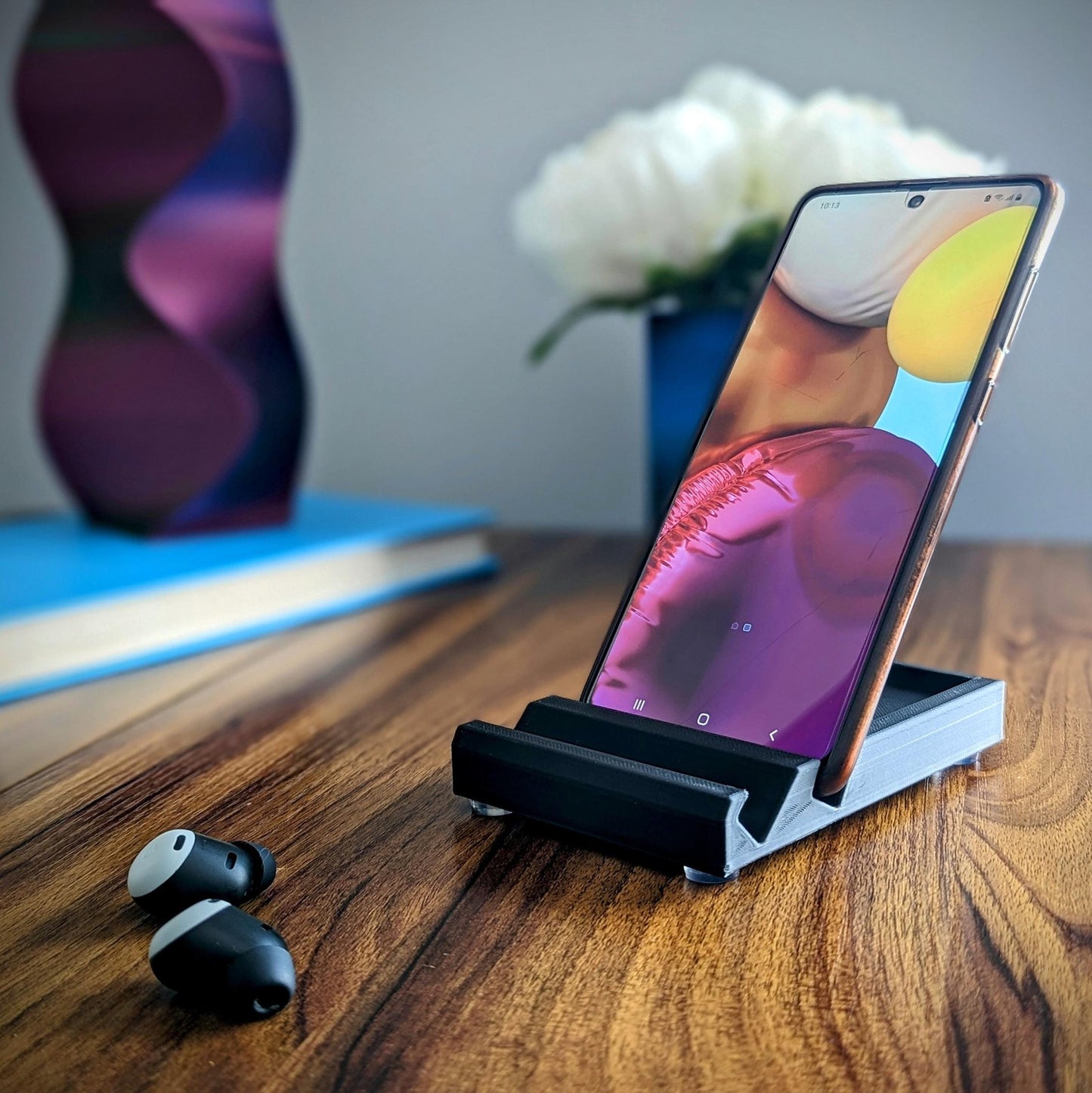 Minimalist phone holder with two display vantage angles. Back tray ideal for storing air pods or earbuds. Comes in a variety of colors and may be customized for the dimensions of any device.