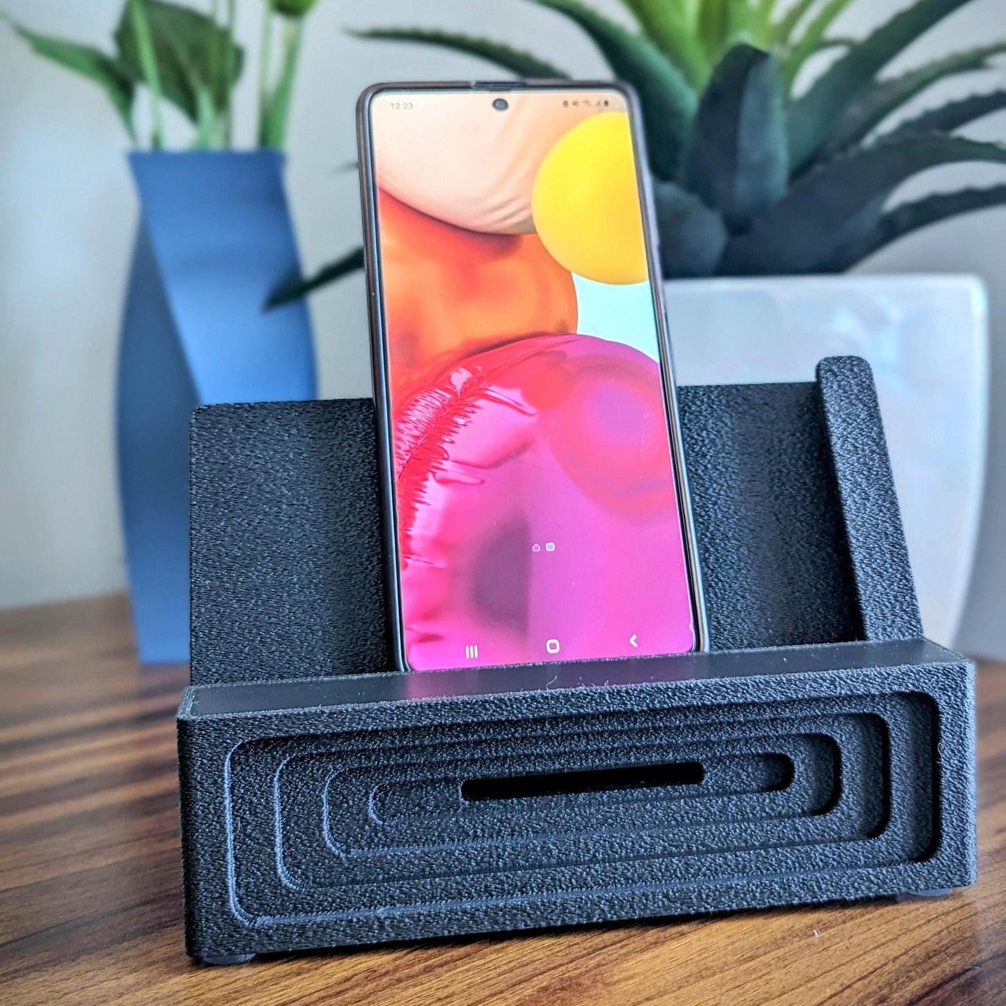 Phone stand with acoustic booster ideal for movie viewing. Back tray ideal for storing air pods or earbuds. Comes in a variety of colors and compatible with nearly all phones.