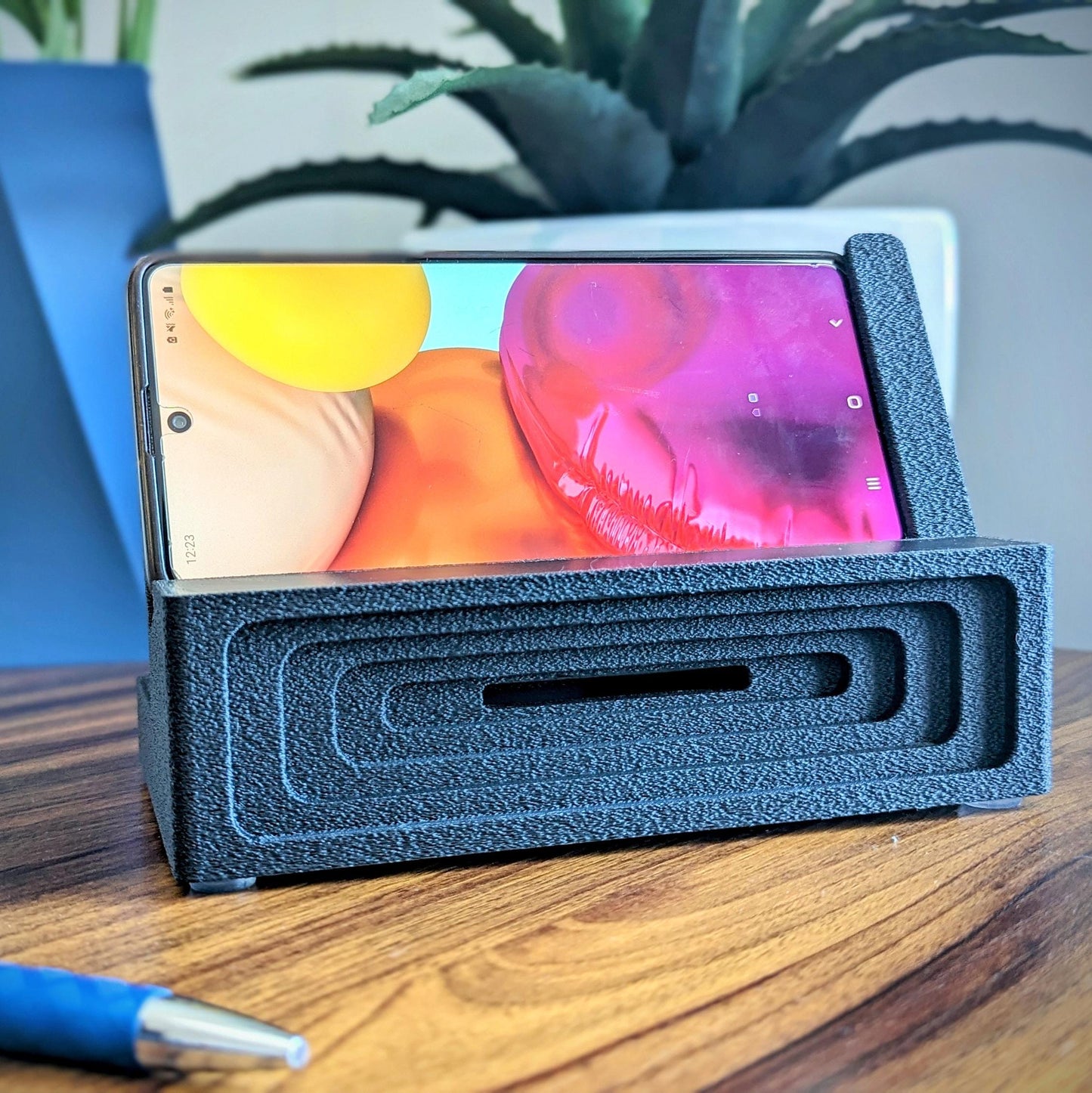 Phone stand with acoustic booster ideal for movie viewing. Back tray ideal for storing air pods or earbuds. Comes in a variety of colors and compatible with nearly all phones.