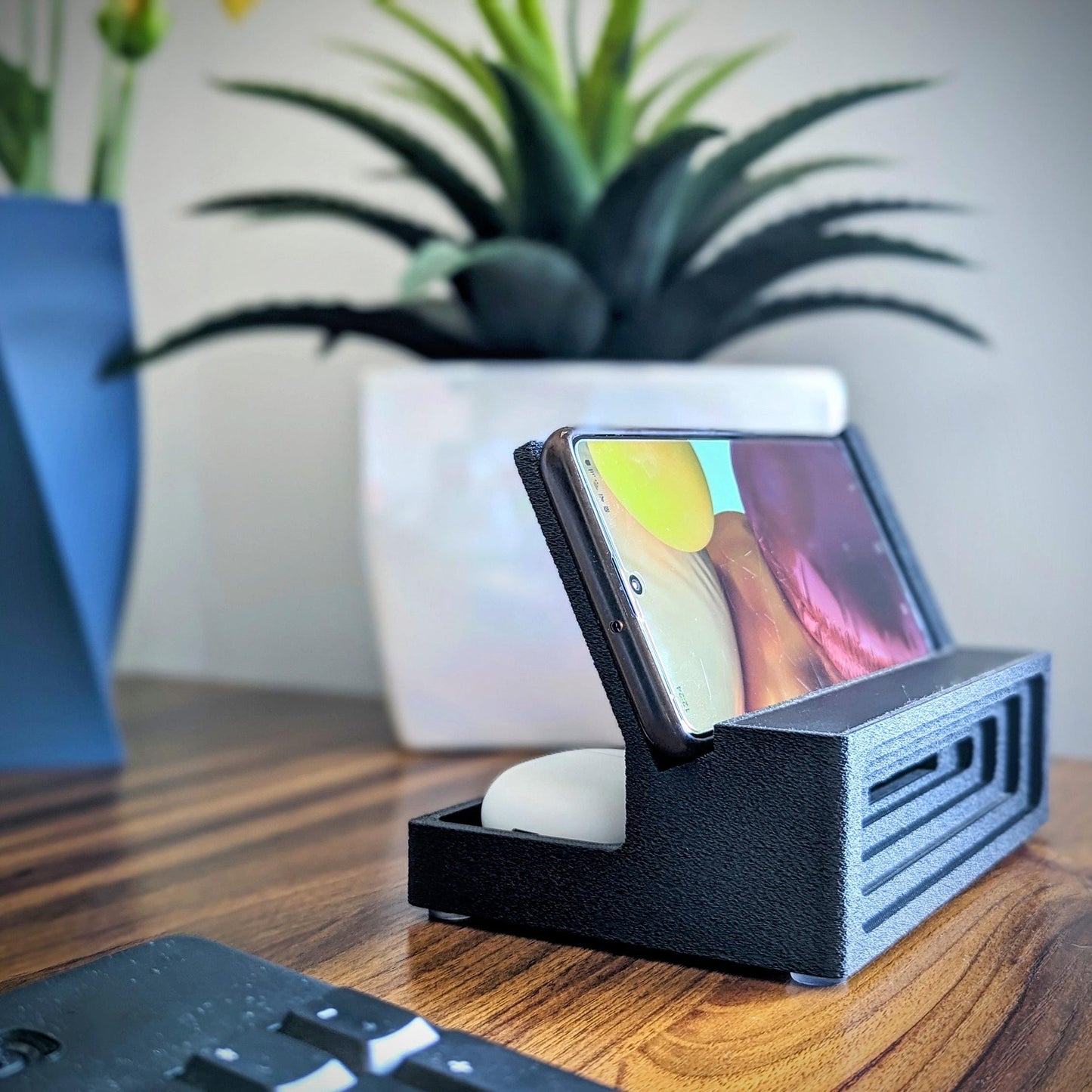 Phone stand with acoustic booster ideal for movie viewing. Back tray ideal for storing air pods or earbuds. Comes in a variety of colors and compatible with nearly all phones.