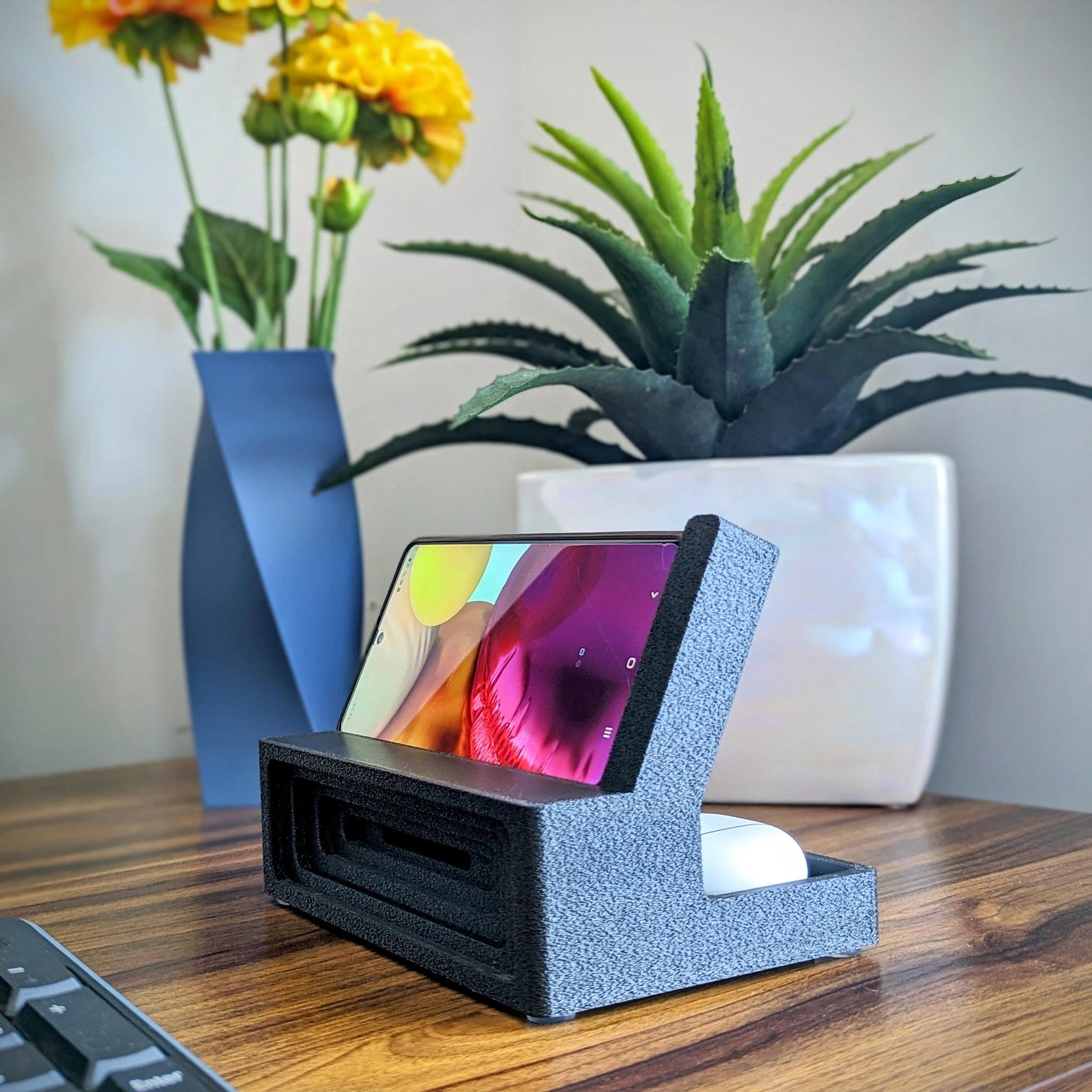 Phone stand with acoustic booster ideal for movie viewing. Back tray ideal for storing air pods or earbuds. Comes in a variety of colors and compatible with nearly all phones.